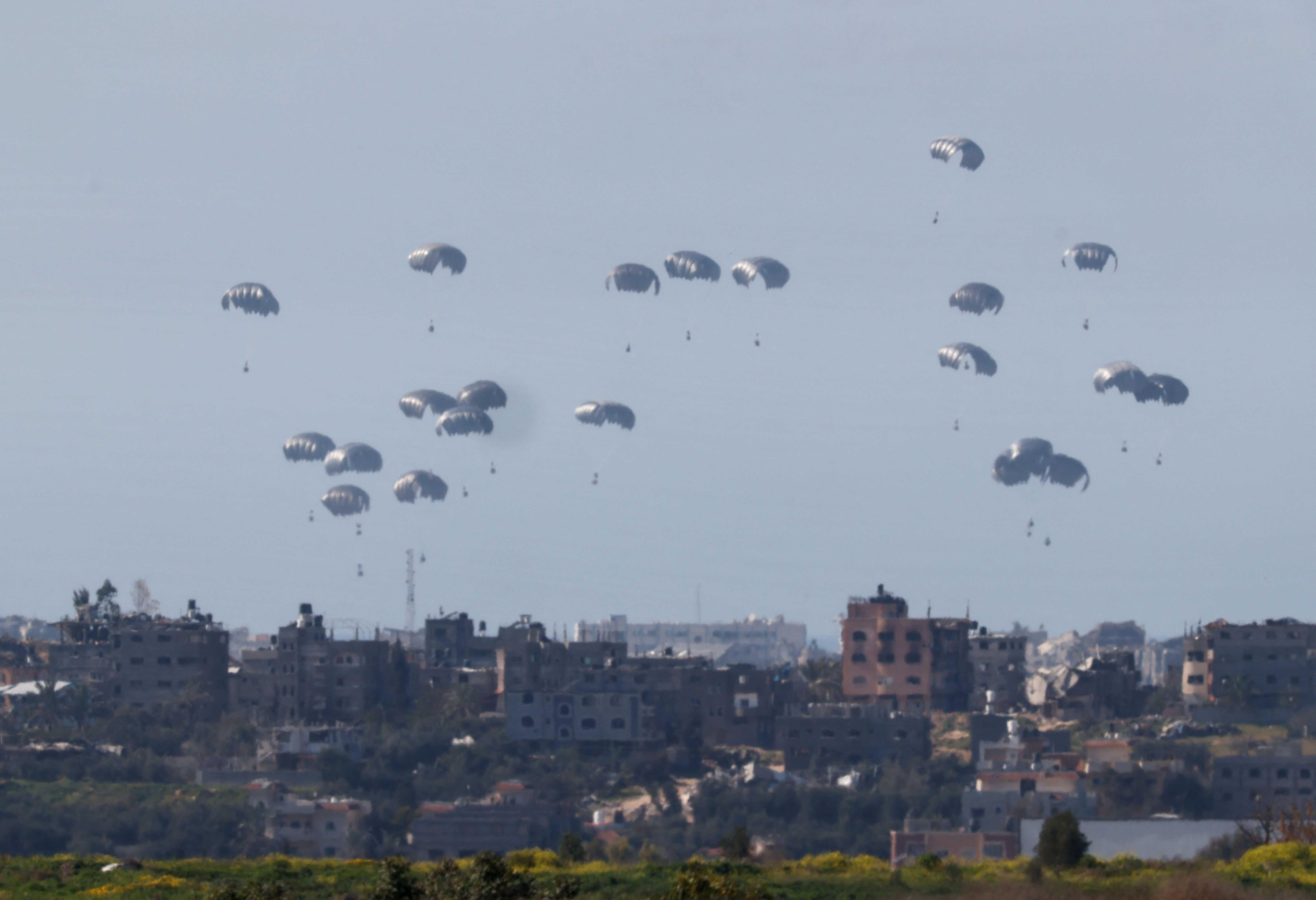 Packages dropped from a military aircraft fall towards Gaza, as seen from Israel