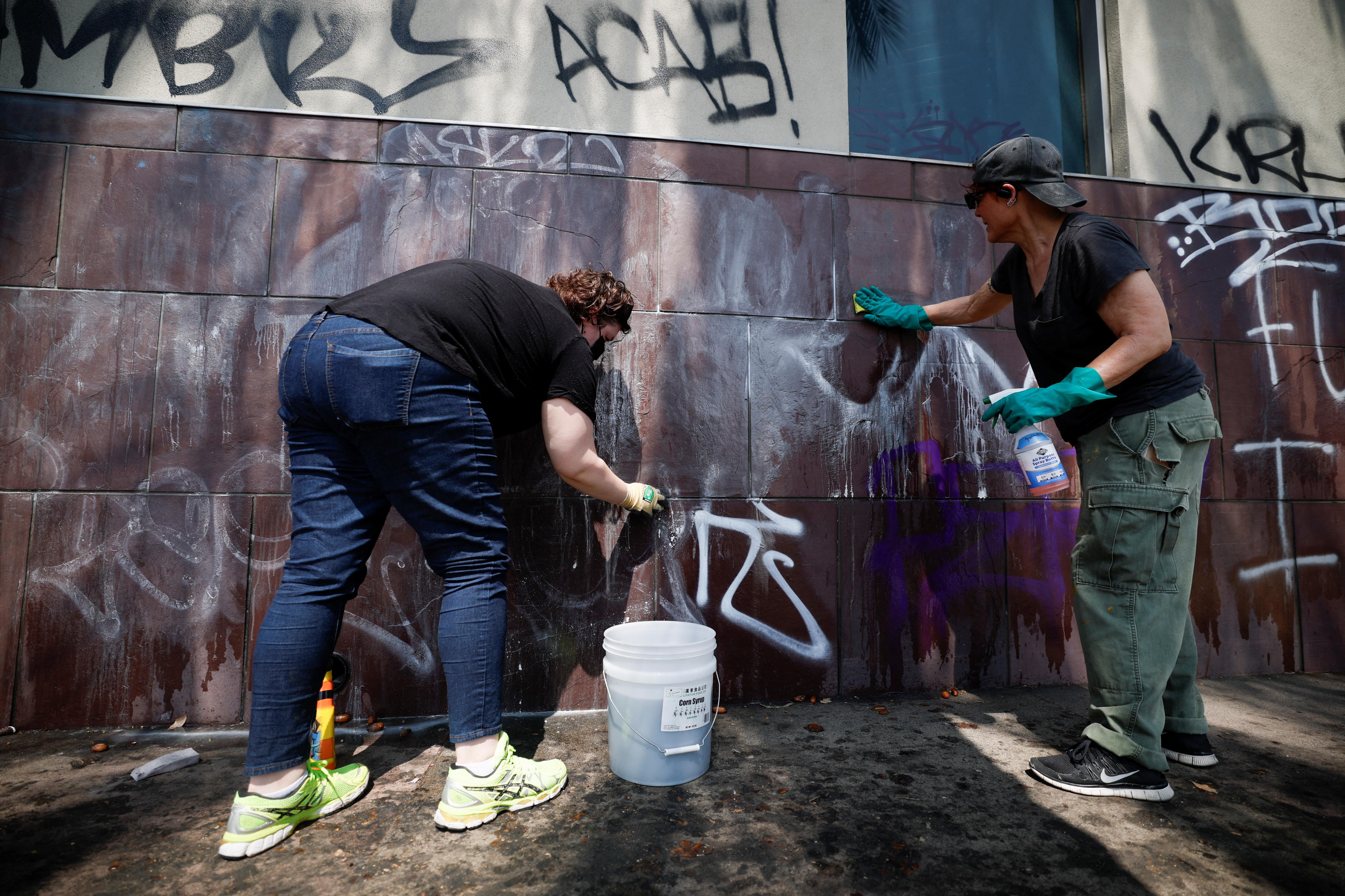 Social activists and artists take graffiti off from the Japanese American National Museum, after days of protests against federal immigration sweeps, in downtown Los Angeles