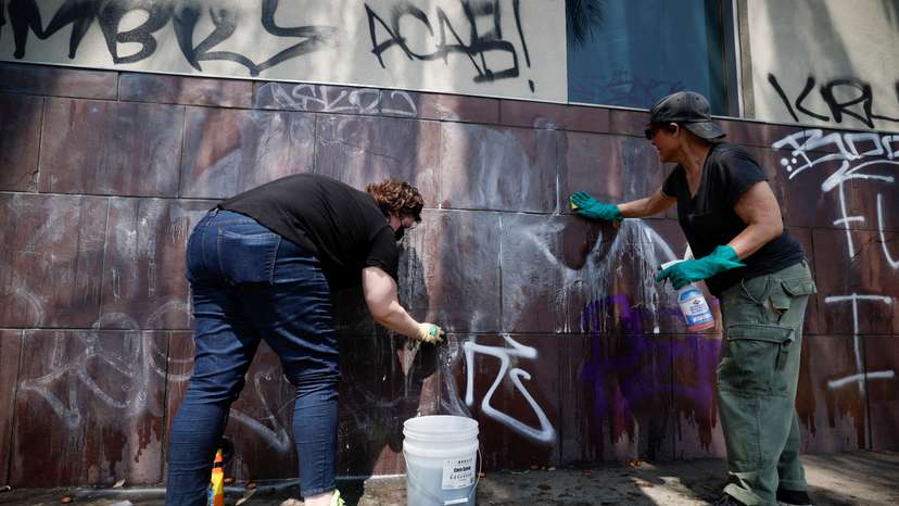 Social activists and artists take graffiti off from the Japanese American National Museum, after days of protests against federal immigration sweeps, in downtown Los Angeles