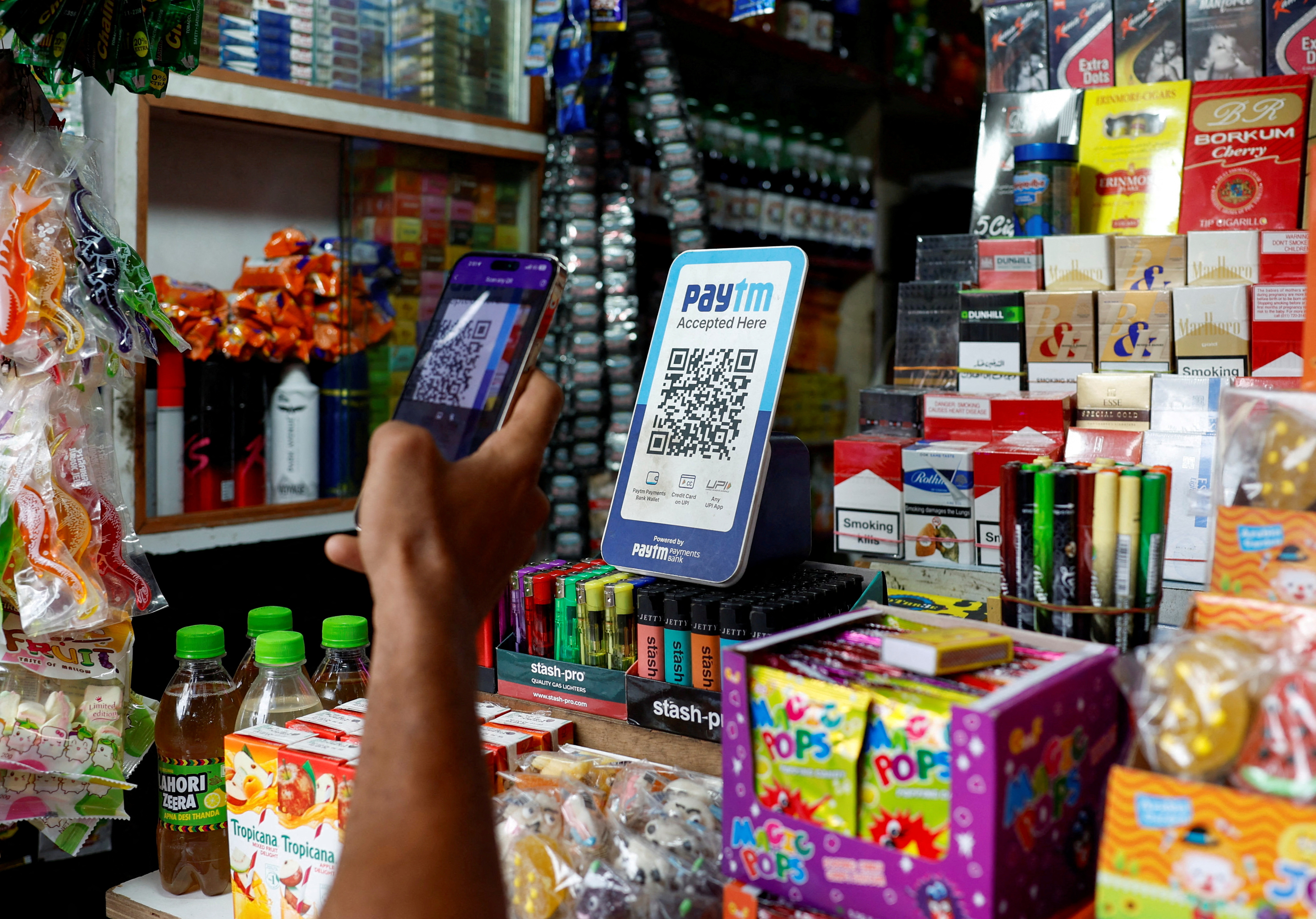 FILE PHOTO: A man uses his phone to scan a QR code of the digital payment app Paytm after purchasing a cold beverage at a shop in Kolkata