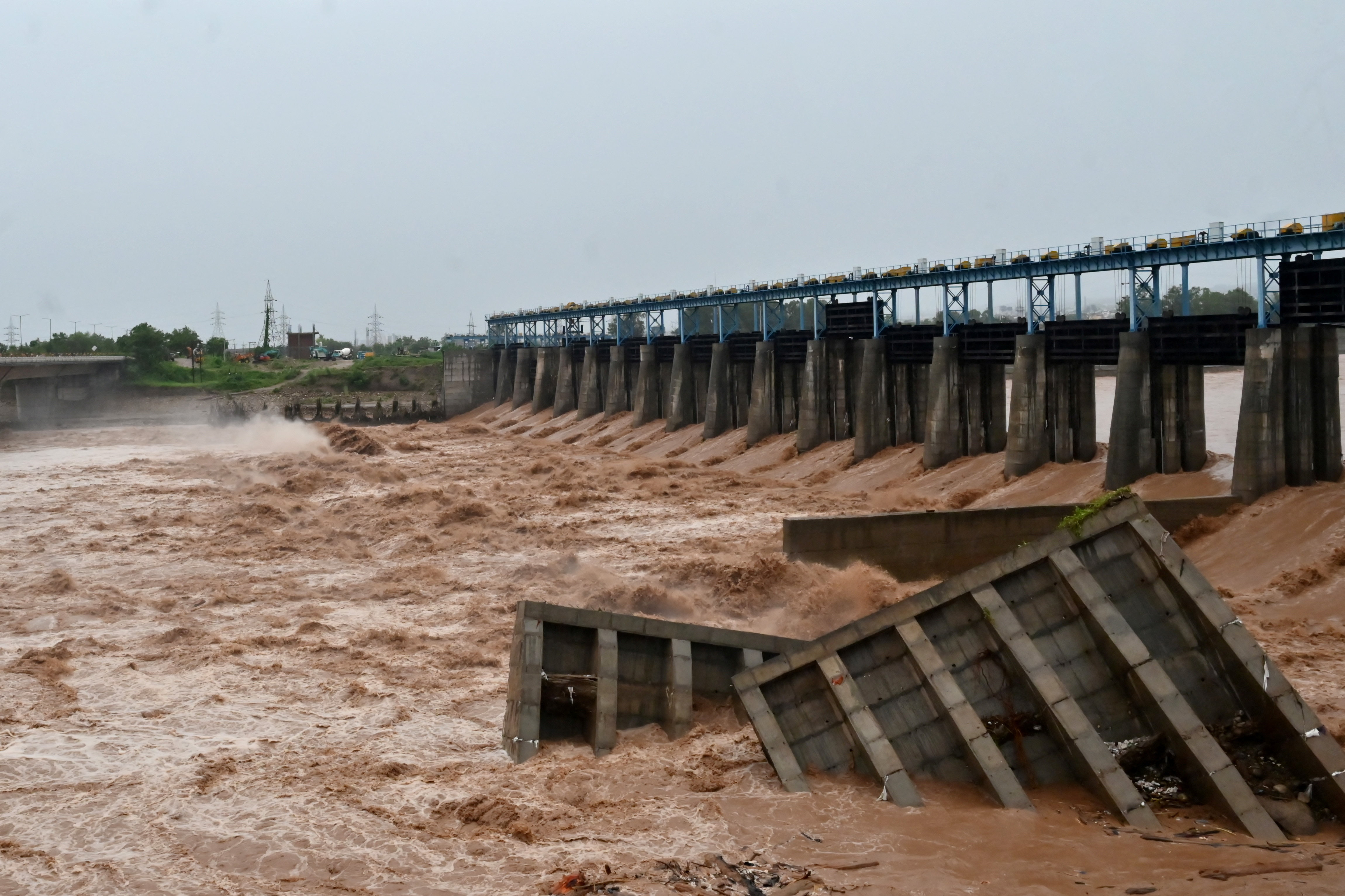 Damaged cemented blocks lie in the water beside an under-construction dam on the Tawi River, following heavy rainfall in Jammu