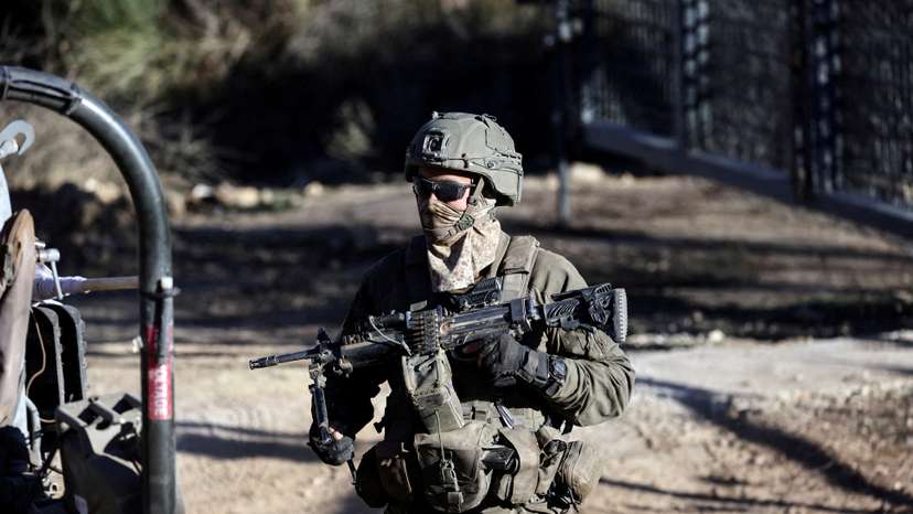 An Israeli soldier stands by the ceasefire line between the Israeli-occupied Golan Heights and Syria, as seen from Majdal Shams in the Golan Heights