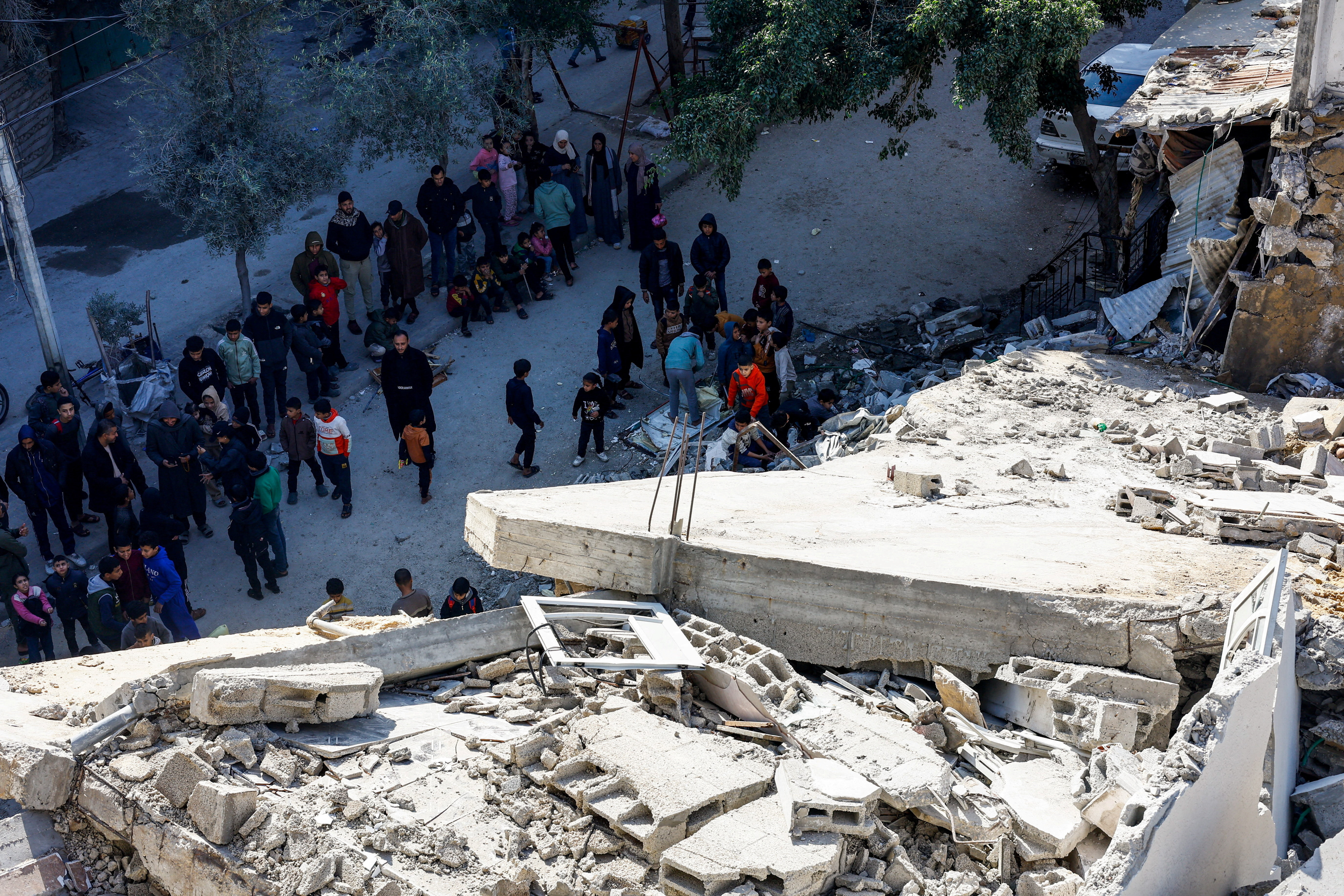 Palestinians at the site of a collapsed house that was damaged during the war by an Israeli strike