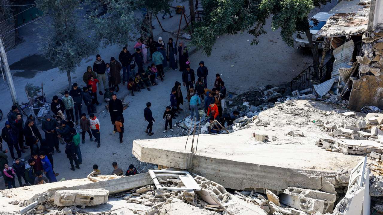 Palestinians at the site of a collapsed house that was damaged during the war by an Israeli strike