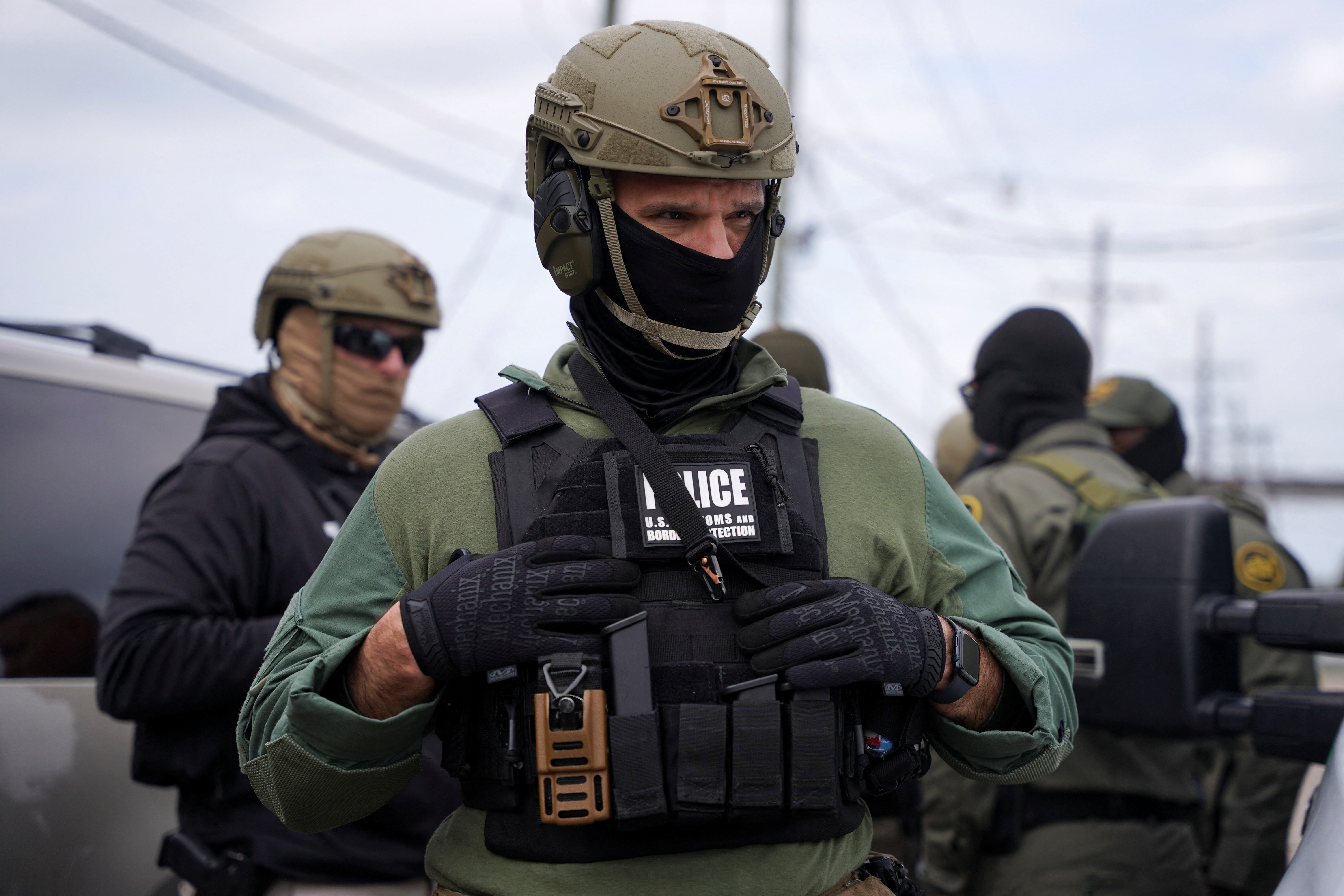 Border Patrol commander Greg Bovino and Border Patrol agents stand on a side street in Kenner