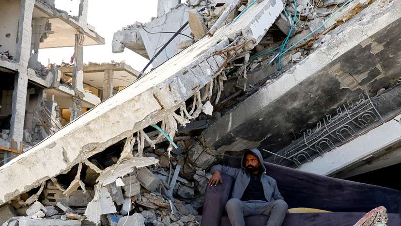A Palestinian man sits amidst the rubble of buildings destroyed during the Israeli offensive, amid a ceasefire between Israel and Hamas, in Rafah