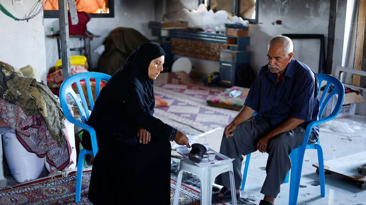 Palestinian couple Mahmoud and Fatima Jarghoun sit inside their damaged home, in Khan Younis
