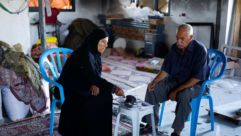 Palestinian couple Mahmoud and Fatima Jarghoun sit inside their damaged home, in Khan Younis
