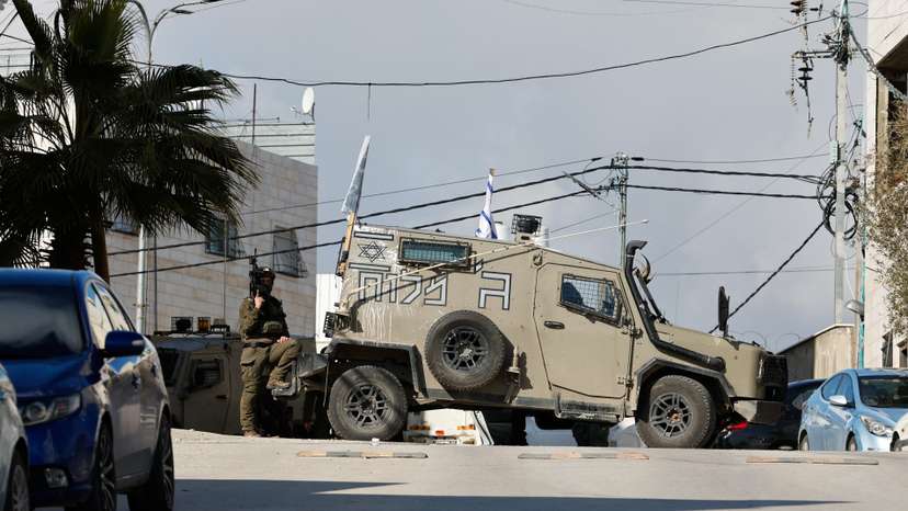 Israeli troops stand guard near a shooting scene in Hebron