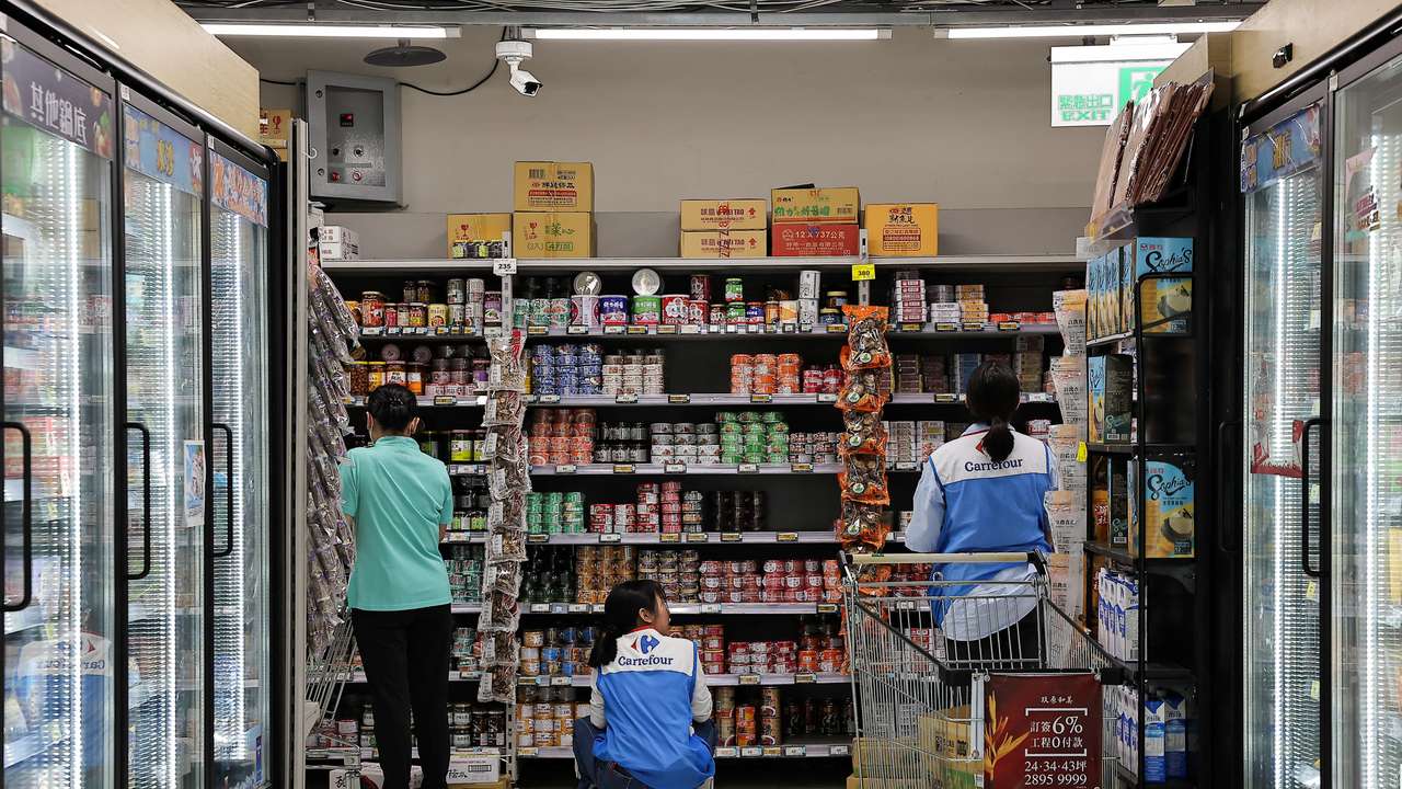 Staff stock canned food at a supermarket ahead of Typhoon Krathon which is expected to intensify and make an unusual landfall