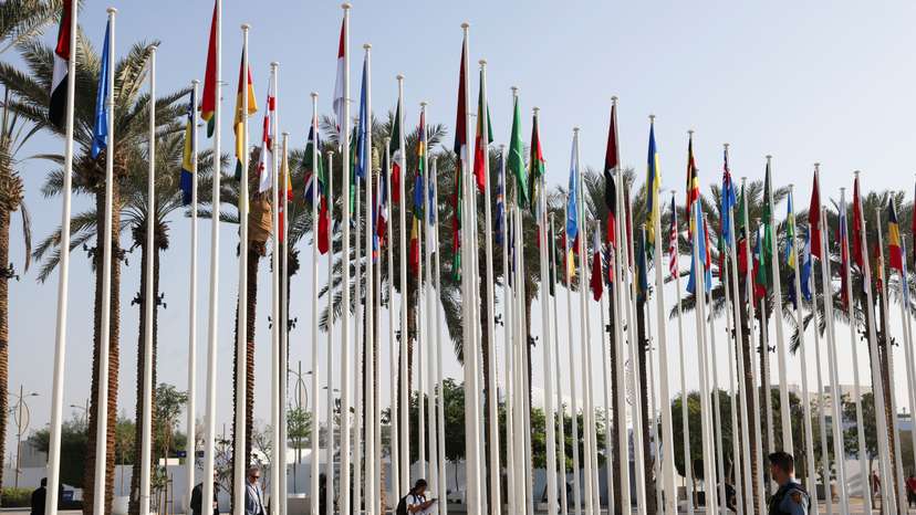 UN security officer walks near the flags at Dubai's Expo City during the United Nations Climate Change Conference (COP28) in Dubai