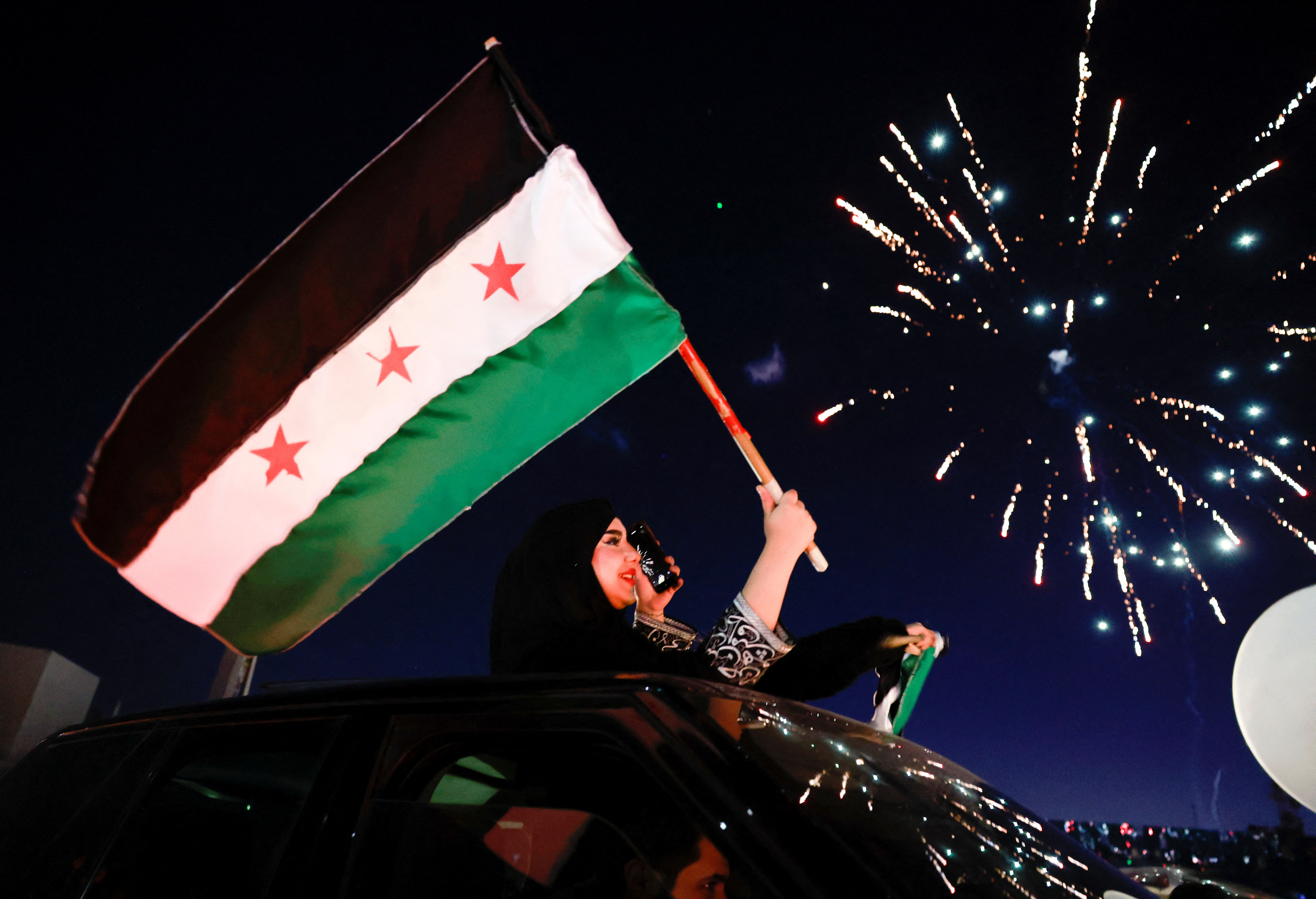 People celebrate after fighters of the ruling Syrian body ousted Syria's Bashar al-Assad, in Damascus