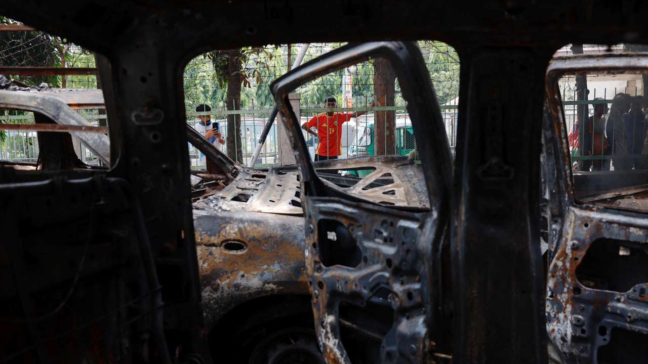 People stand near vandalised cars after Bangladeshi PM Hasina's resignation, in Dhaka