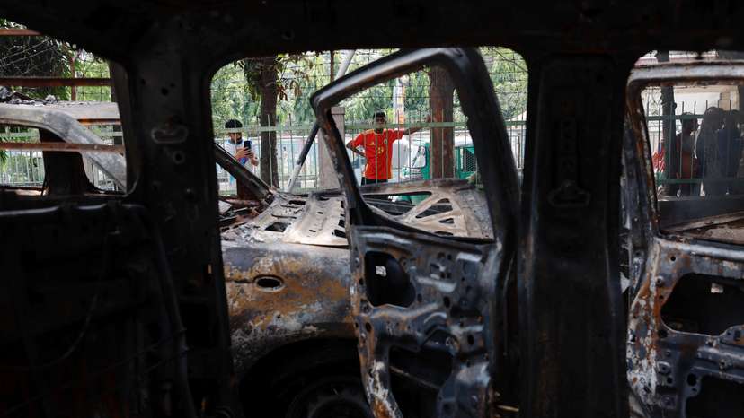 People stand near vandalised cars after Bangladeshi PM Hasina's resignation, in Dhaka