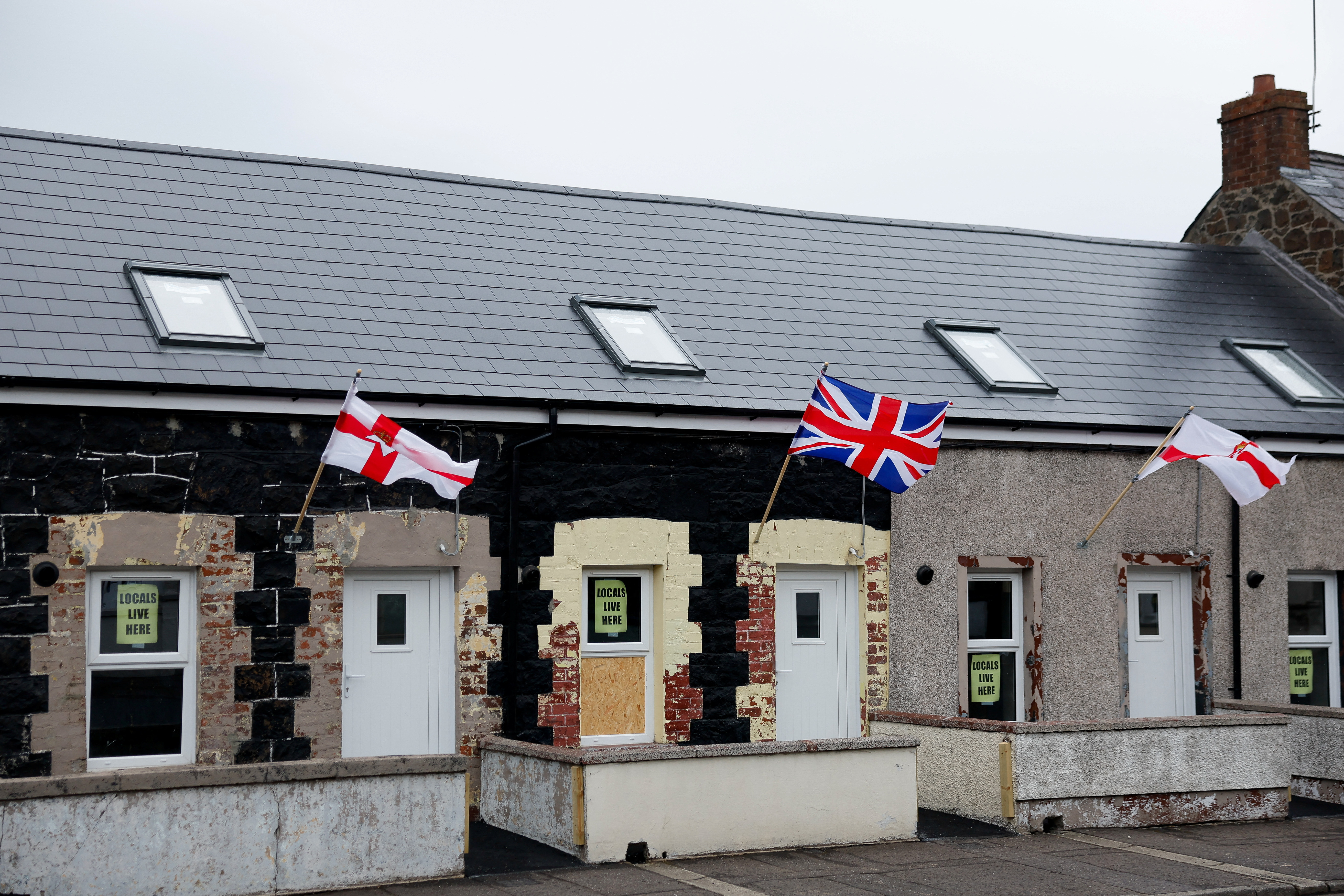 Signs reading: "Locals live here", are displayed on a residential house, in Ballymena