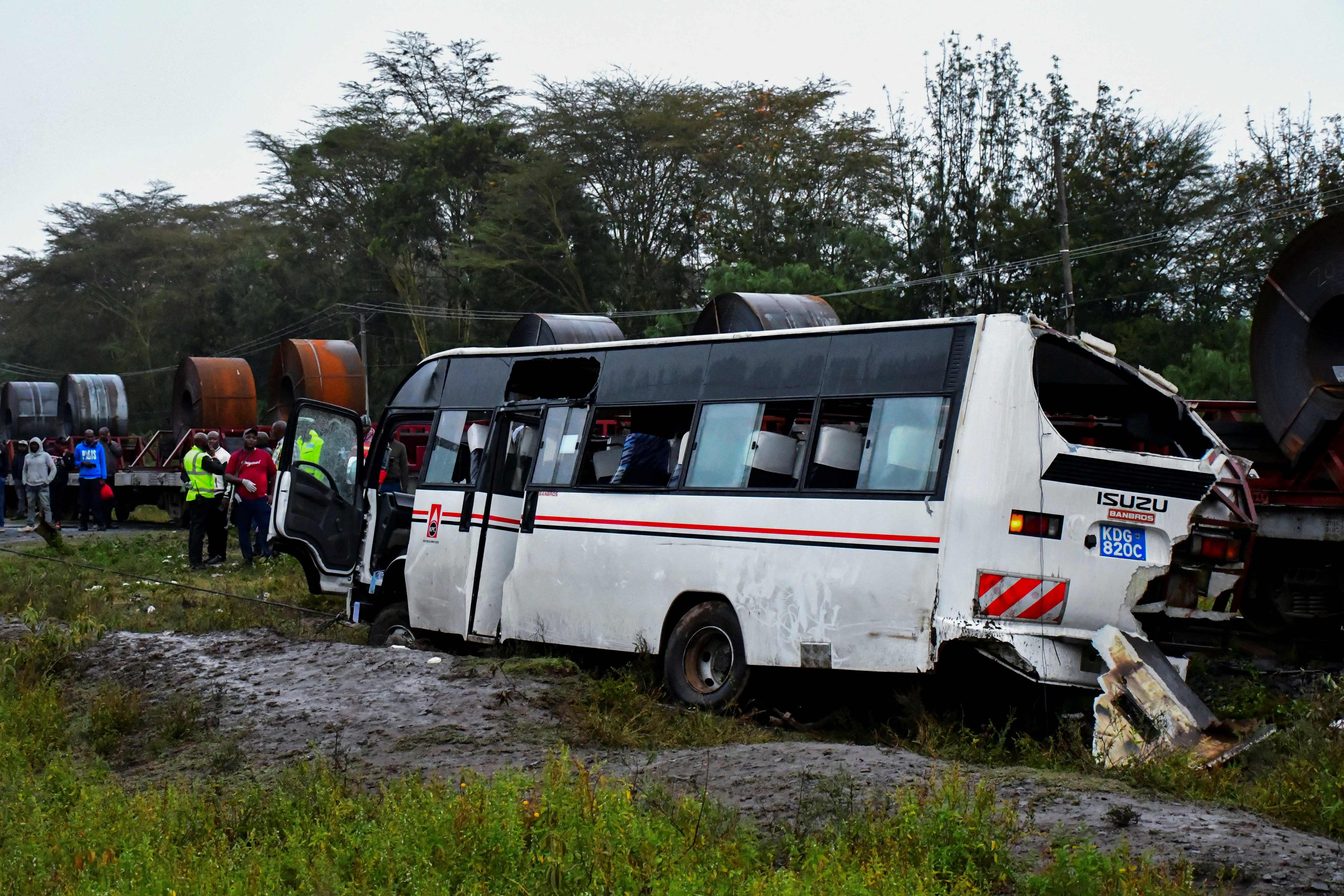 People gather in front of the wreckage of a staff bus that collided at a railway crossing in Naivasha