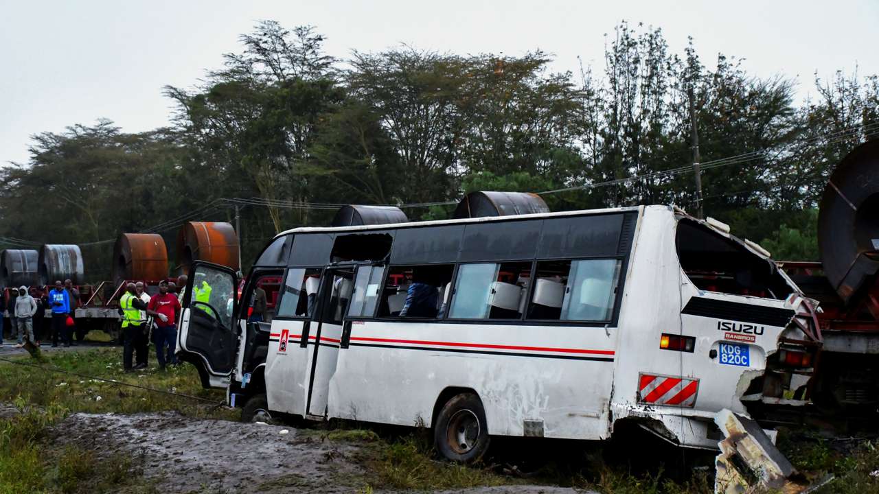 People gather in front of the wreckage of a staff bus that collided at a railway crossing in Naivasha