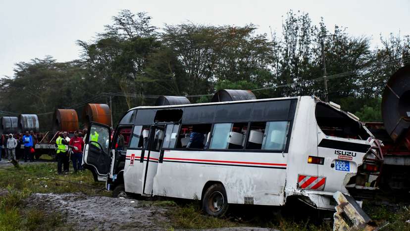 People gather in front of the wreckage of a staff bus that collided at a railway crossing in Naivasha