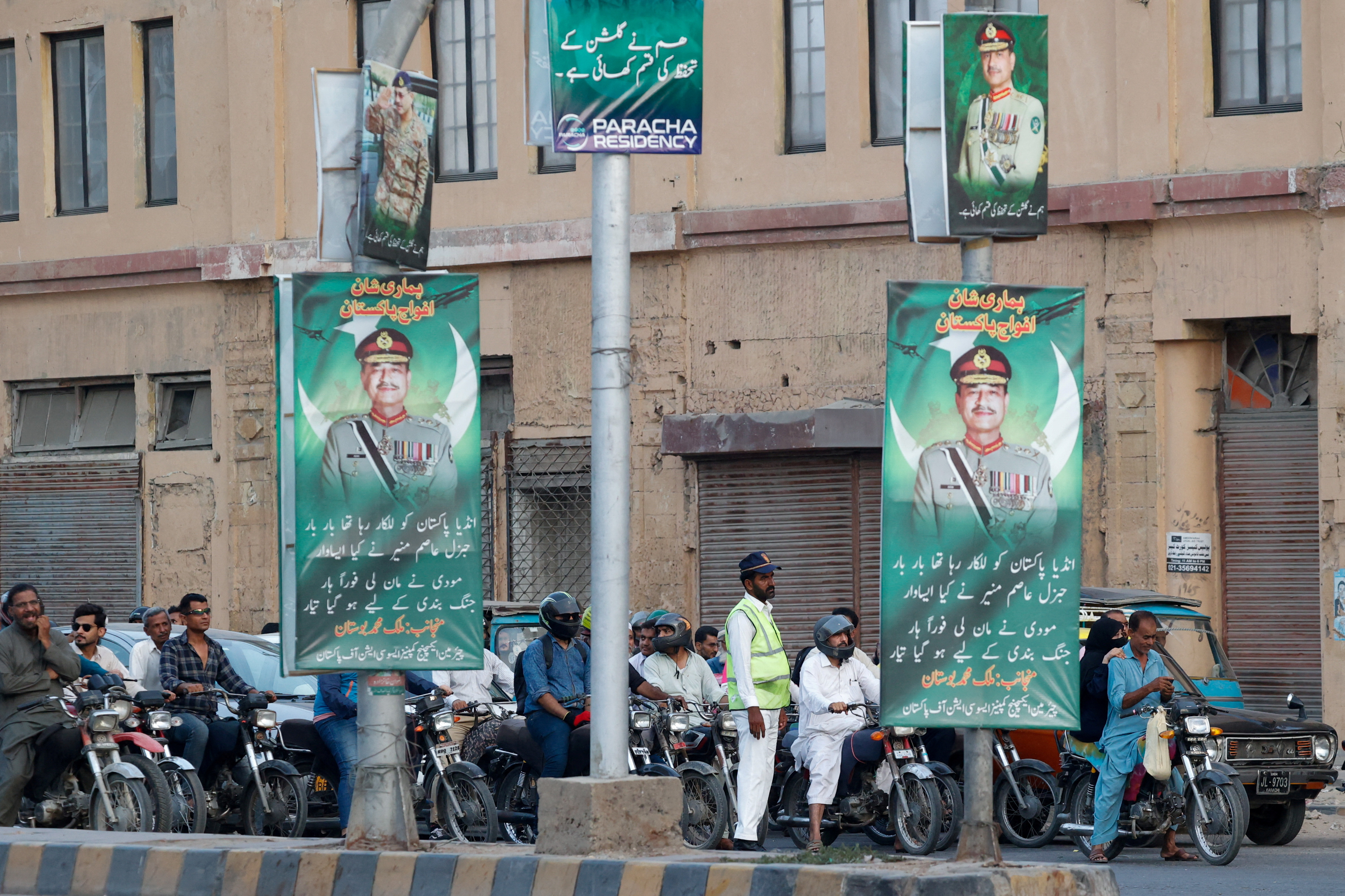 FILE PHOTO: A police officer stands in front of the traffic, next to posters of the Chief of Army Staff of Pakistan Asim Munir, in Karachi