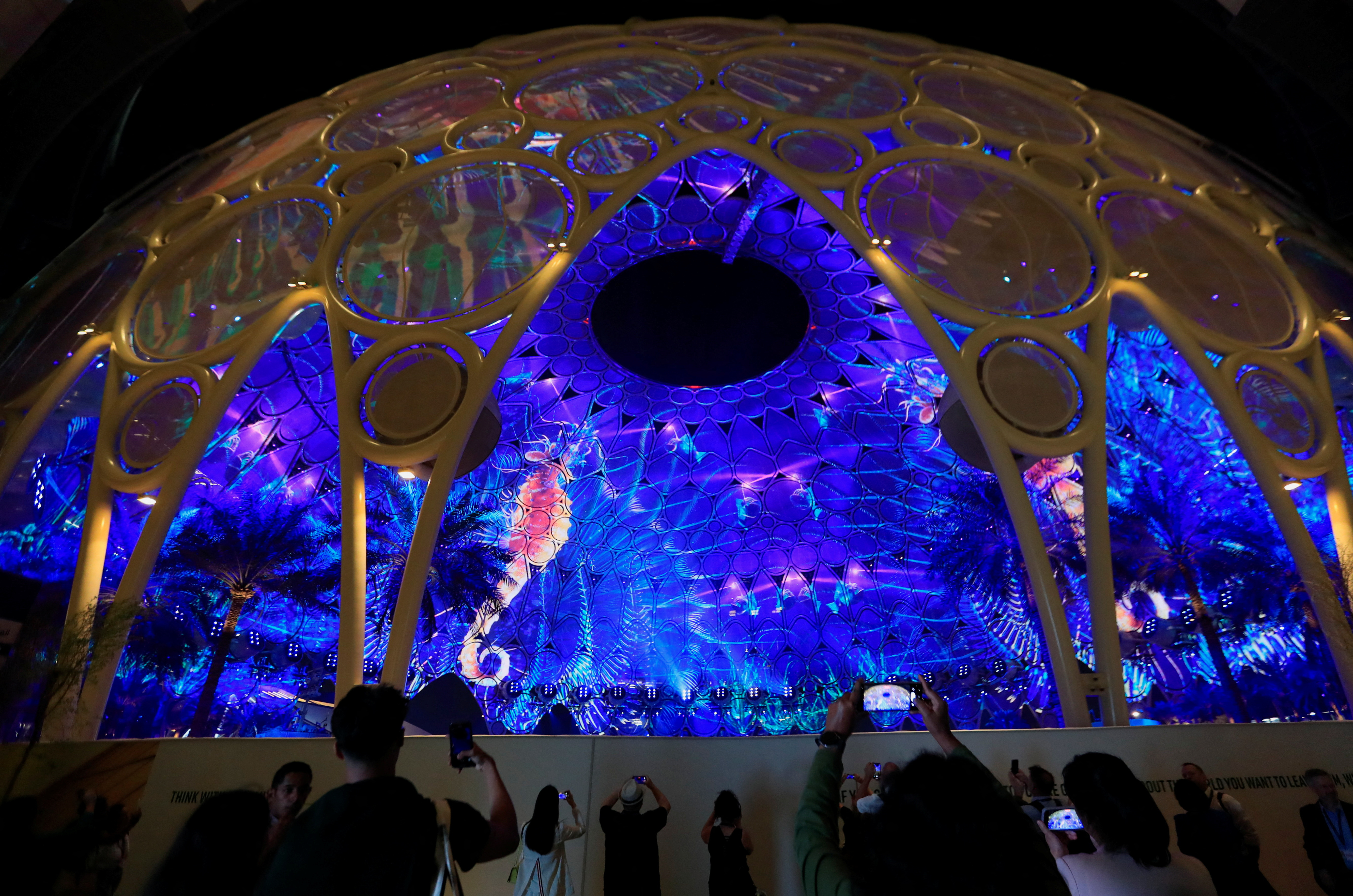 Delegates use their mobile phones to record the projections at the Al Wasl Dome at the Dubai's Expo City during the United Nations Climate Change Conference (COP28) in Dubai