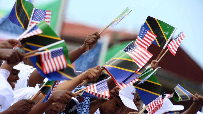 A crowd of people wave both the Tanzanian and United States flags during the welcome ceremony for U.S. President Barack Obama in Dar Es Salaam