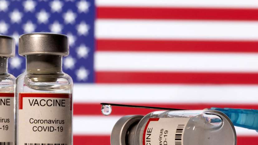 FILE PHOTO: Illustration shows vials labelled "VACCINE Coronavirus COVID-19" and a syringe in front of a displayed U.S. flag