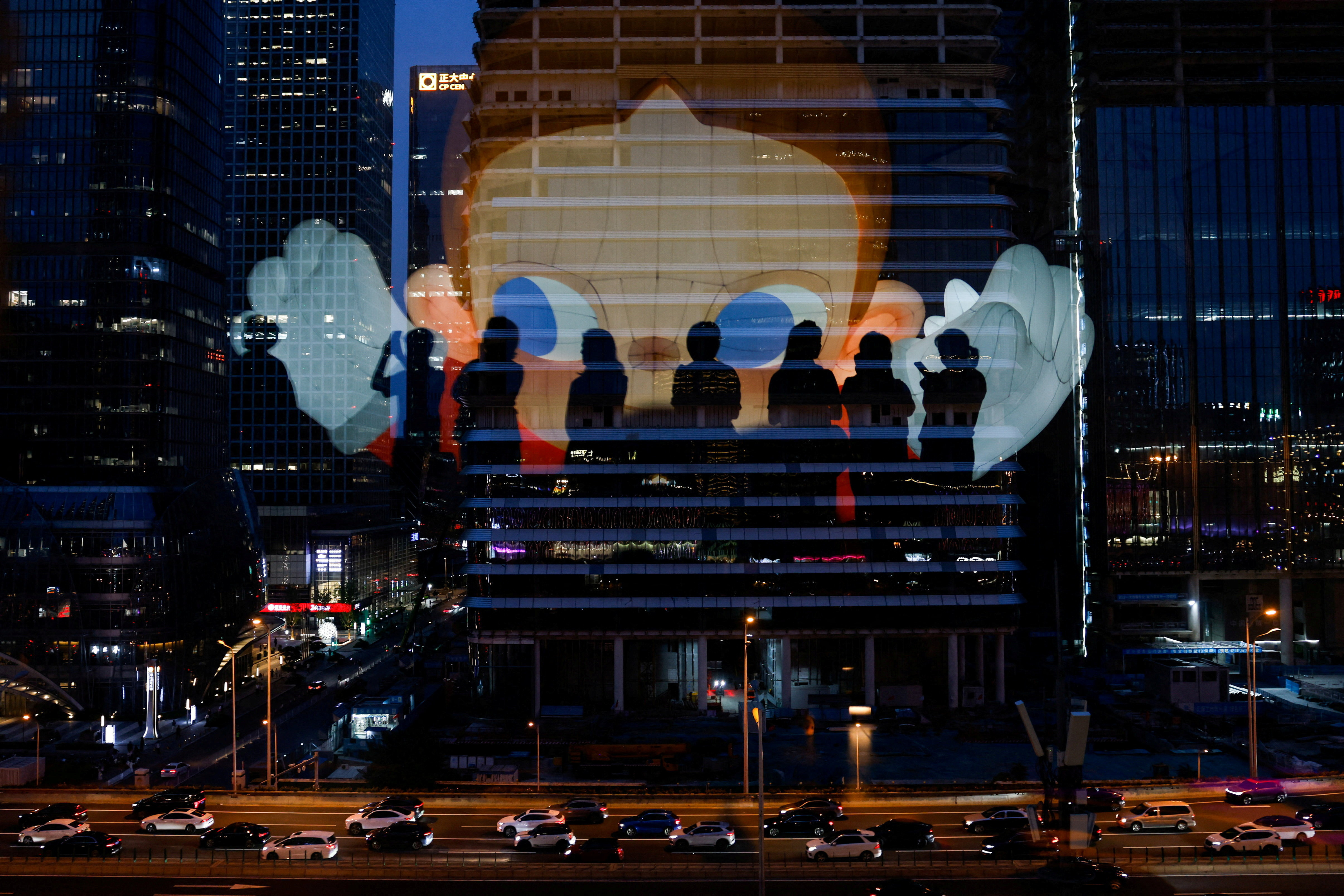 The reflection of silhouettes of people is visible on a glass on a terrace of a shopping mall overlooking Beijing's (CBD)