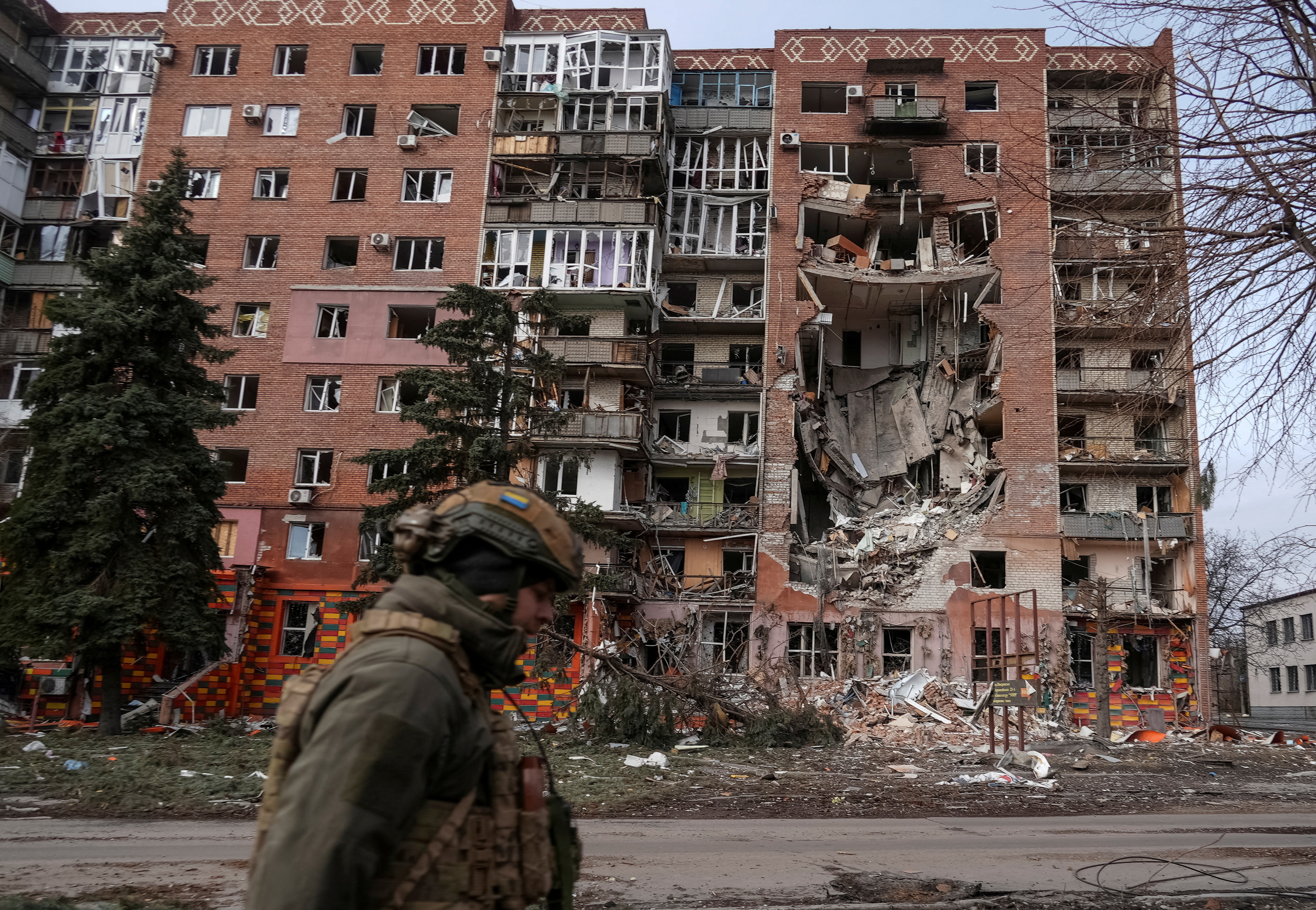 A Ukrainian serviceman passes by a residential building damaged by Russian military strikes in the frontline town of Pokrovsk