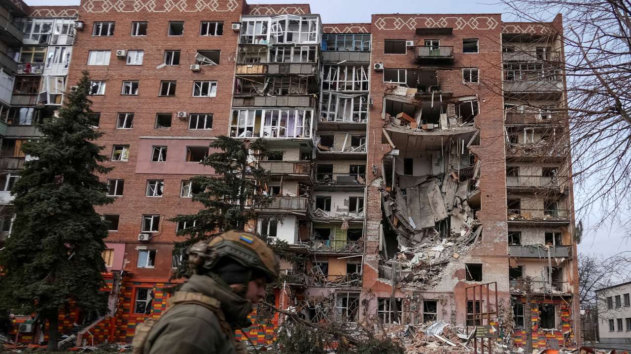 A Ukrainian serviceman passes by a residential building damaged by Russian military strikes in the frontline town of Pokrovsk