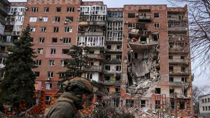 A Ukrainian serviceman passes by a residential building damaged by Russian military strikes in the frontline town of Pokrovsk