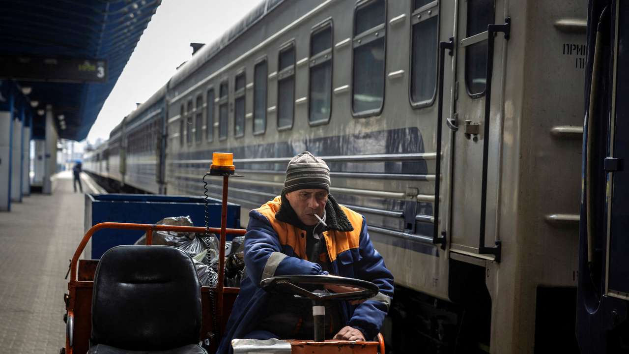 FILE PHOTO: A worker of the Ukrzaliznytsia Ukrainian Railway company drives a luggage cart past a stationary train at the main train station in Kyiv