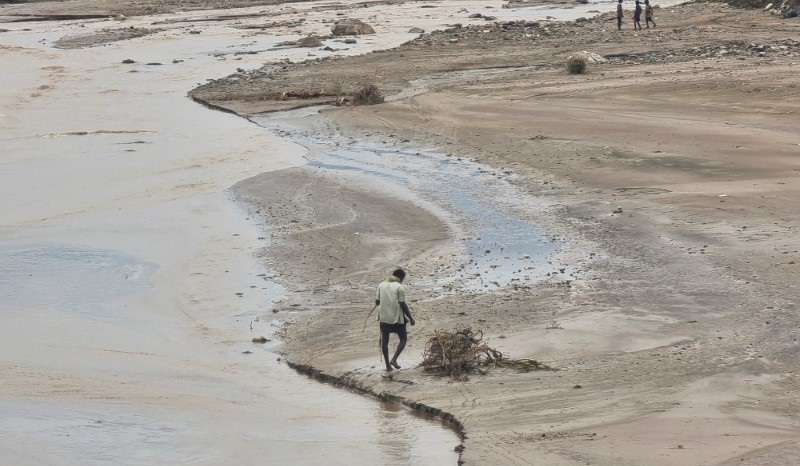 Man walks near flood water following heavy rains in Hajjah