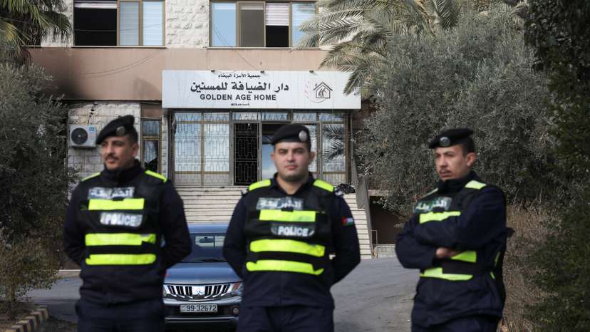 Jordanian police officers stand guard, after a fire broke out early on Friday at a private elderly care center in the Jordanian capital Amman