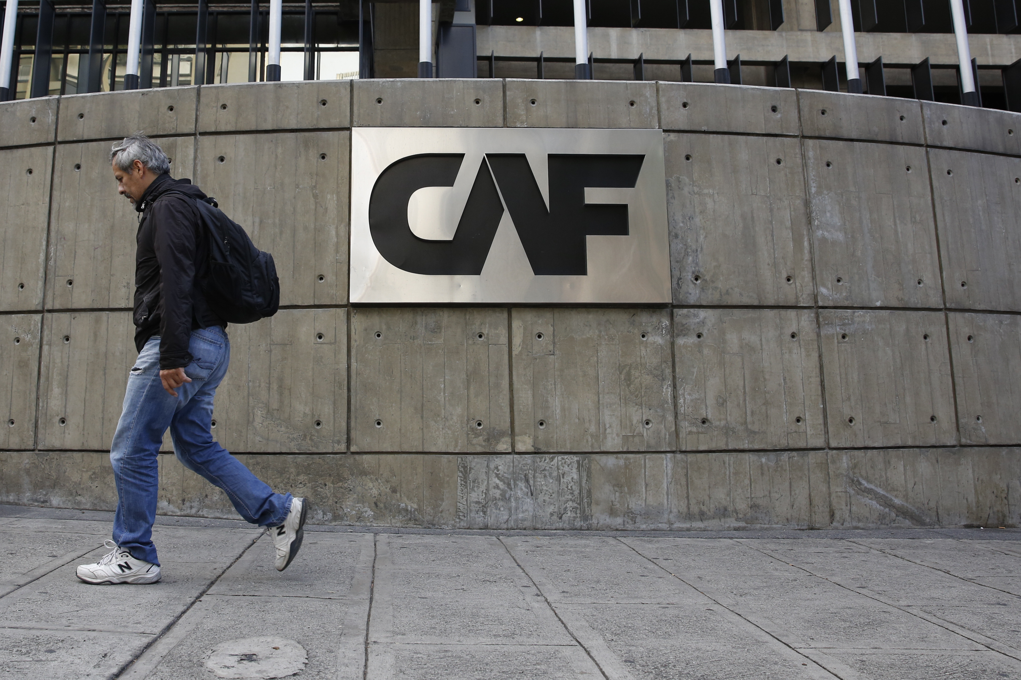 A man walks past the corporate logo of the Development Bank of Latin America at its headquarters in Caracas