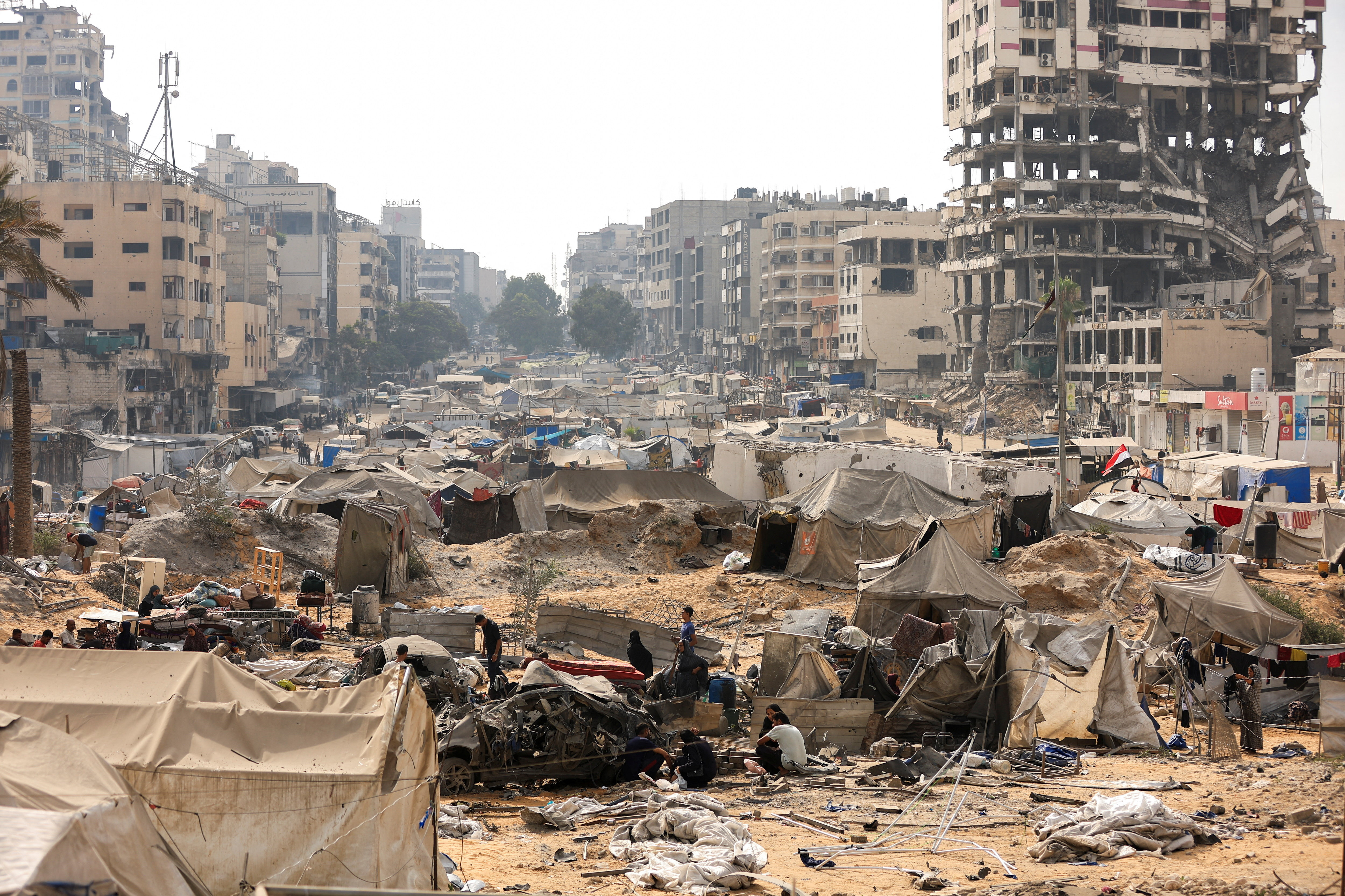 Palestinians inspect a tent camp, which was sheltering displaced people, after it was damaged in an overnight Israeli air strike on a nearby residential building, in Gaza City