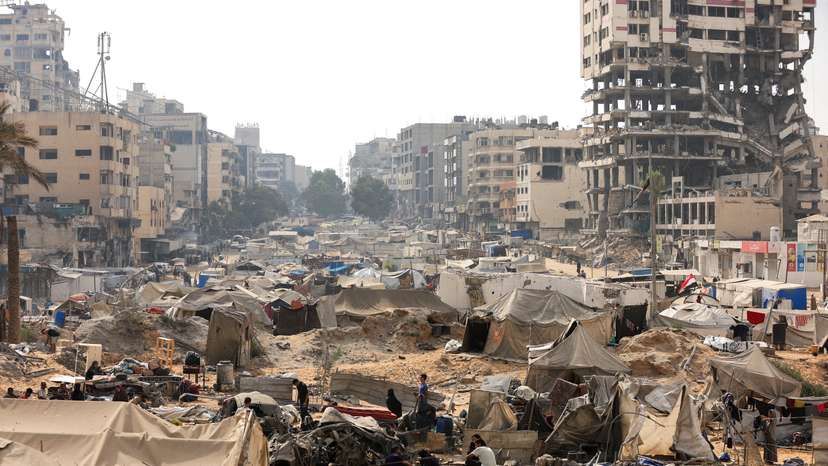 Palestinians inspect a tent camp, which was sheltering displaced people, after it was damaged in an overnight Israeli air strike on a nearby residential building, in Gaza City