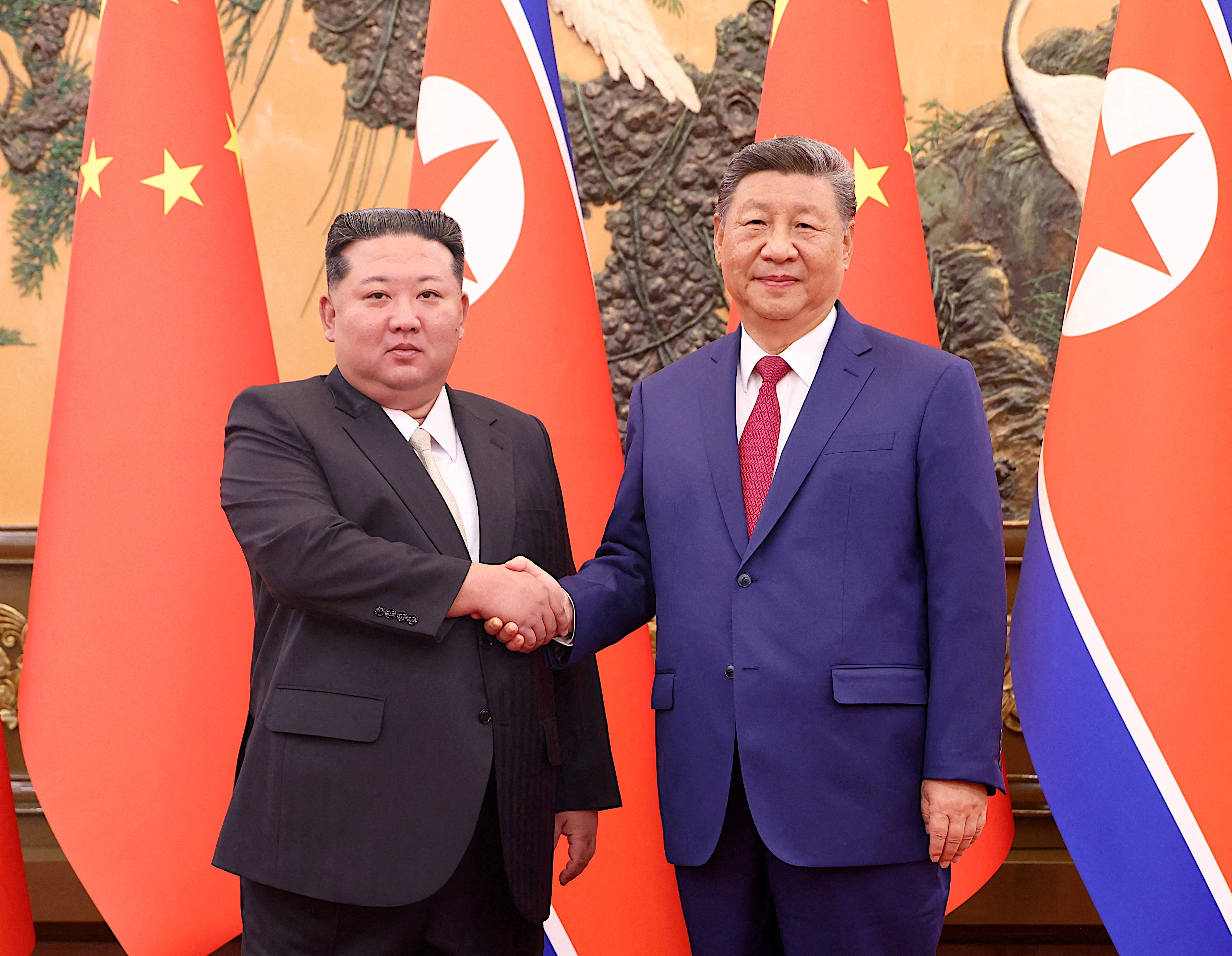 Chinese President Xi Jinping and DPRK leader Kim Jong Un shake hands in Beijing