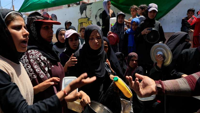 Palestinians gather to receive food from a charity kitchen in Nuseirat