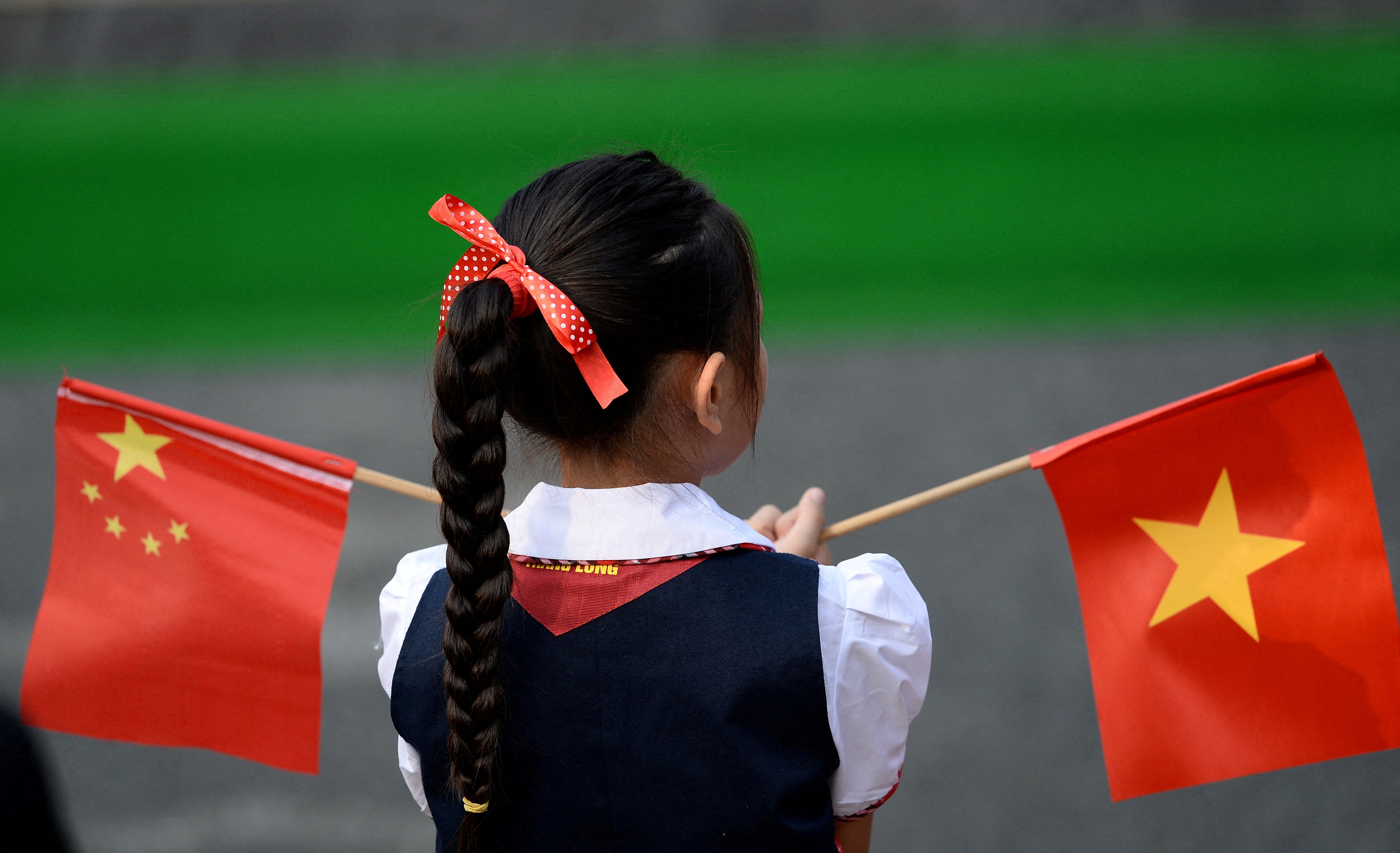 FILE PHOTO: A Vietnamese pupil holds Vietnamese and Chinese flags before the welcoming ceremony at the Presidential Palace in Hanoi