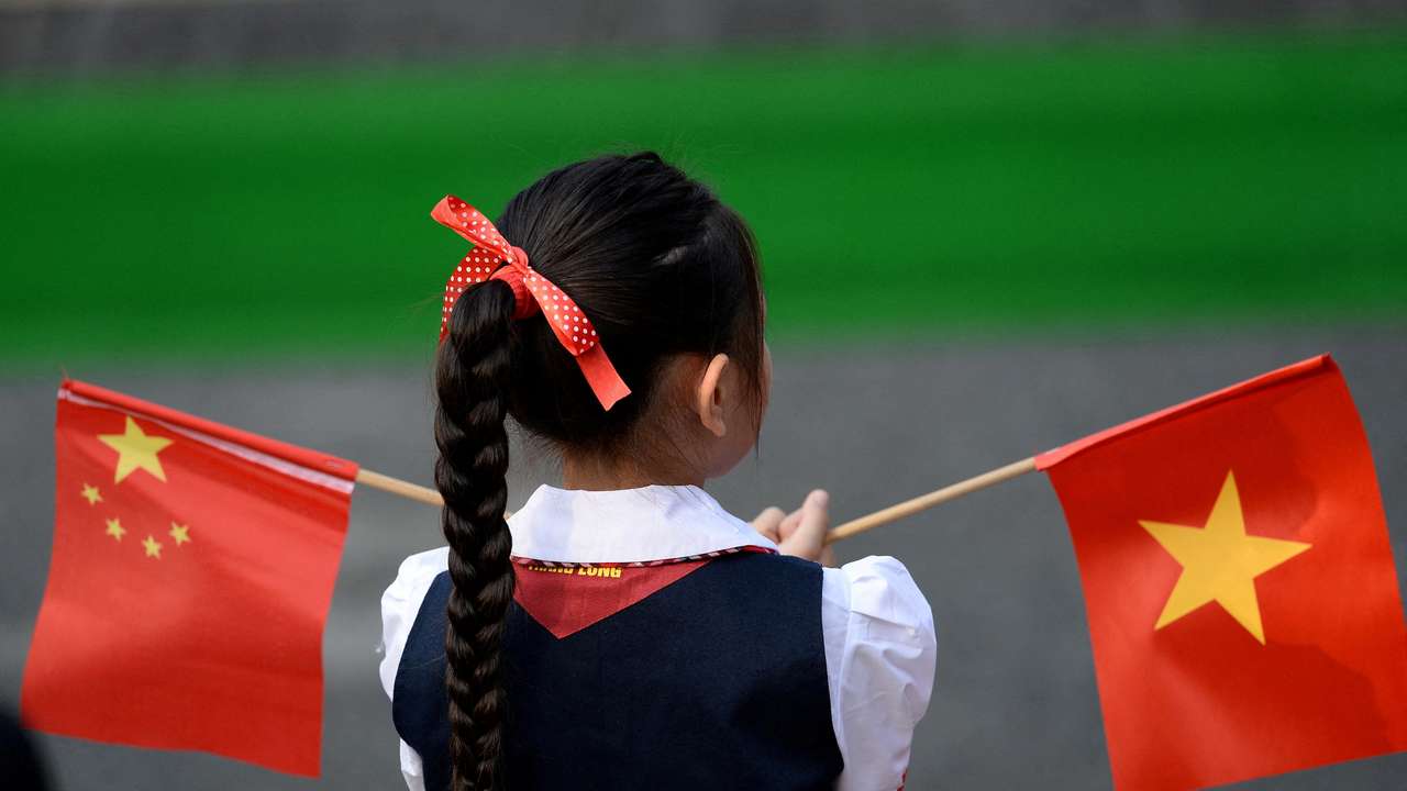 FILE PHOTO: A Vietnamese pupil holds Vietnamese and Chinese flags before the welcoming ceremony at the Presidential Palace in Hanoi