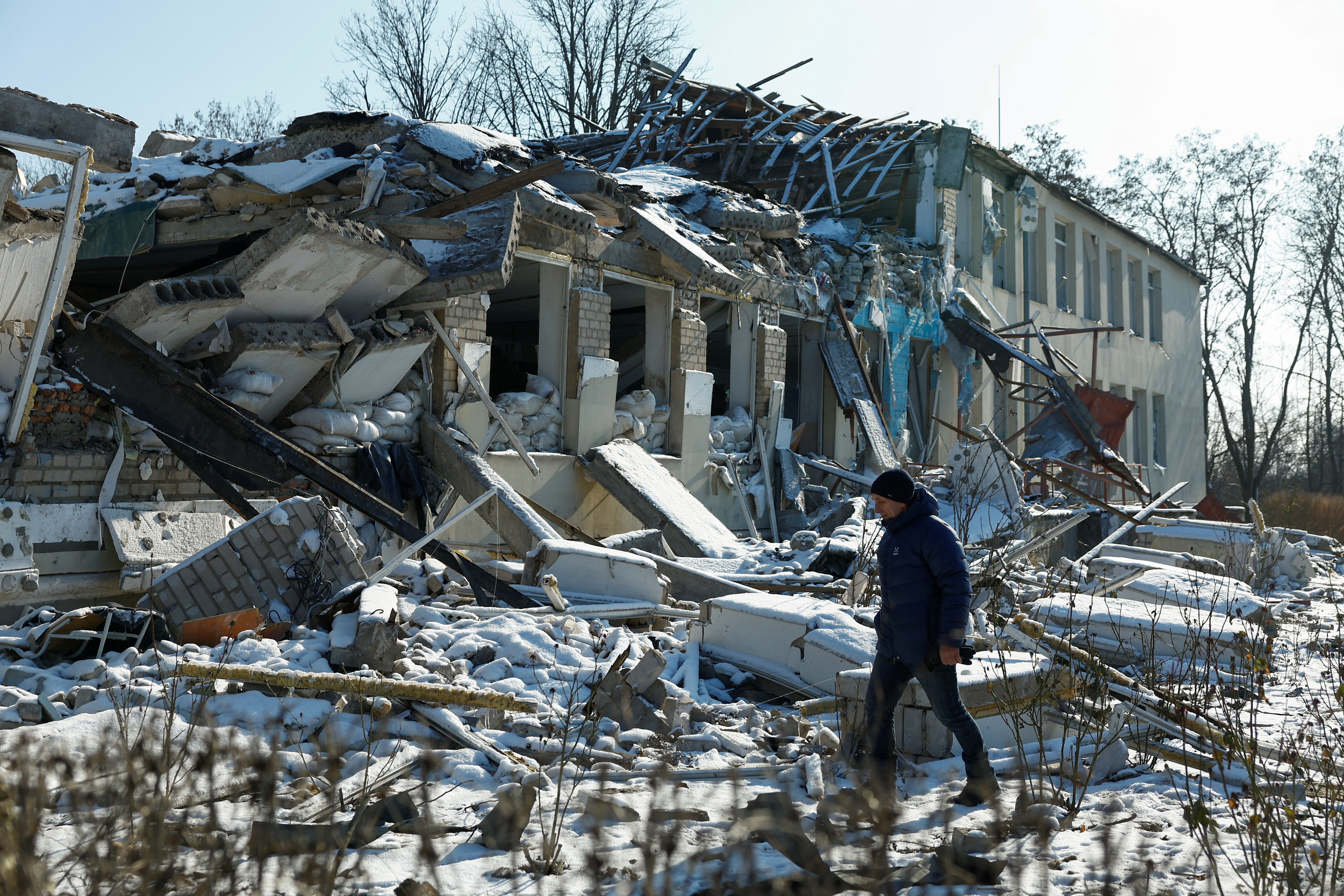 Director of a local lyceum Yurii Bilyk walks next to its building  destroyed by a recent Russian air strike in the village of Novopavlivka