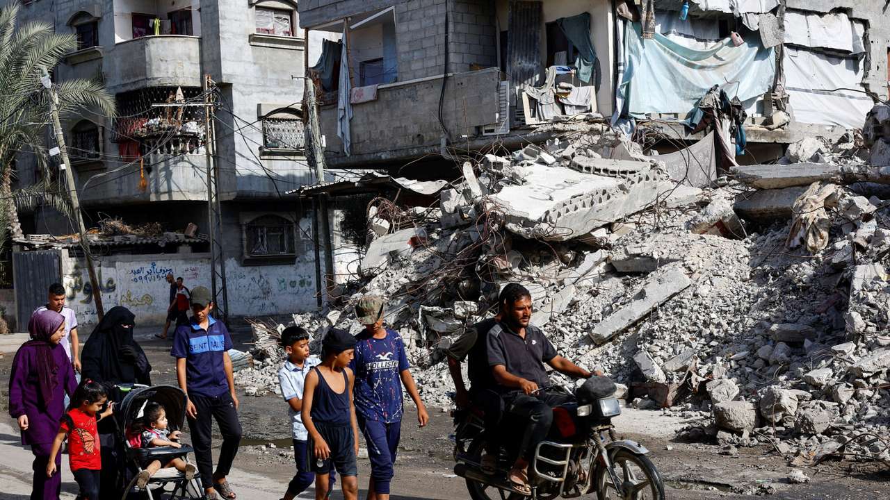 Palestinians walk past a residential building destroyed in previous Israeli strikes, after Hamas agreed to release hostages and accept some other terms in a U.S. plan to end the war, in Nuseirat