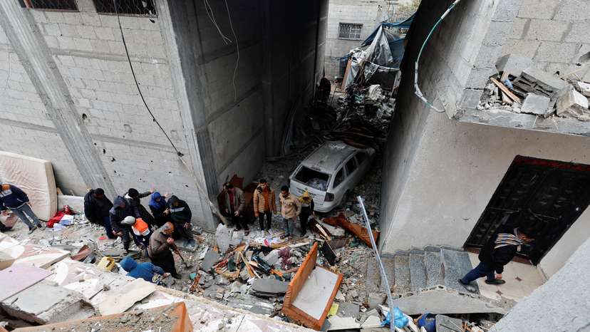 Palestinians inspect the site of an Israeli strike on a house in Rafah