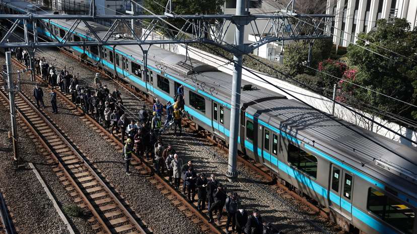 Passengers evacuated from a stranded train on Keihin-Tohoku line stand on a railway track as they head to Tamachi station in Tokyo
