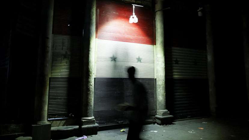 A man walks next to a closed shop painted with a Syrian flag, in Damascus