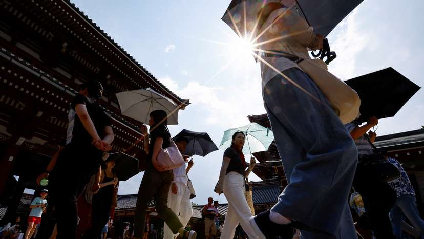Passersby holding umbrellas walk under a strong sunlight at Sensoji temple as Japanese government issued heat stroke alerts in Tokyo