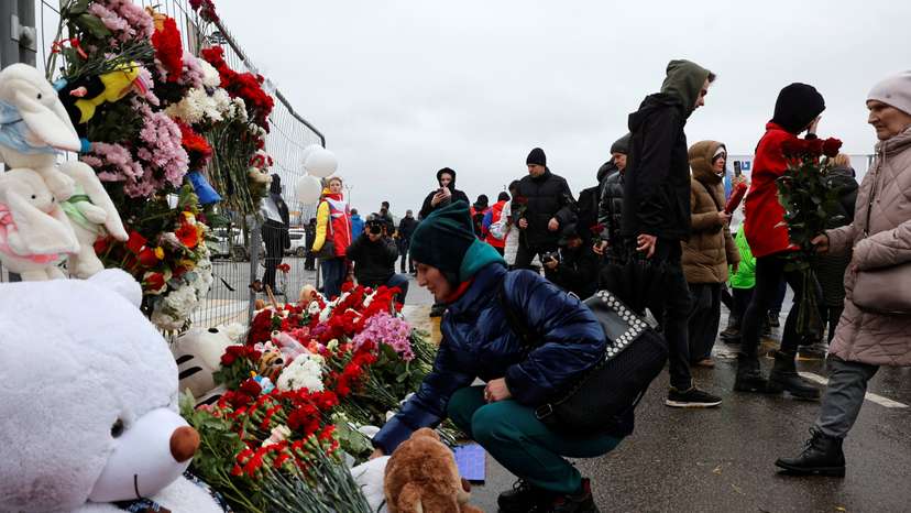 People lay flowers at a makeshift memorial to the victims of a shooting attack at a concert hall outside Moscow