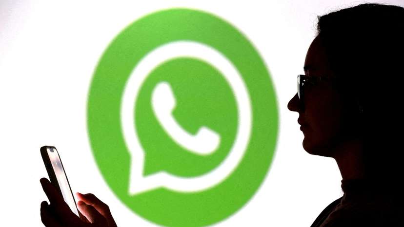 FILE PHOTO: llustration shows a teenager posing for a photo while holding a smartphone in front of a Whatsapp logo