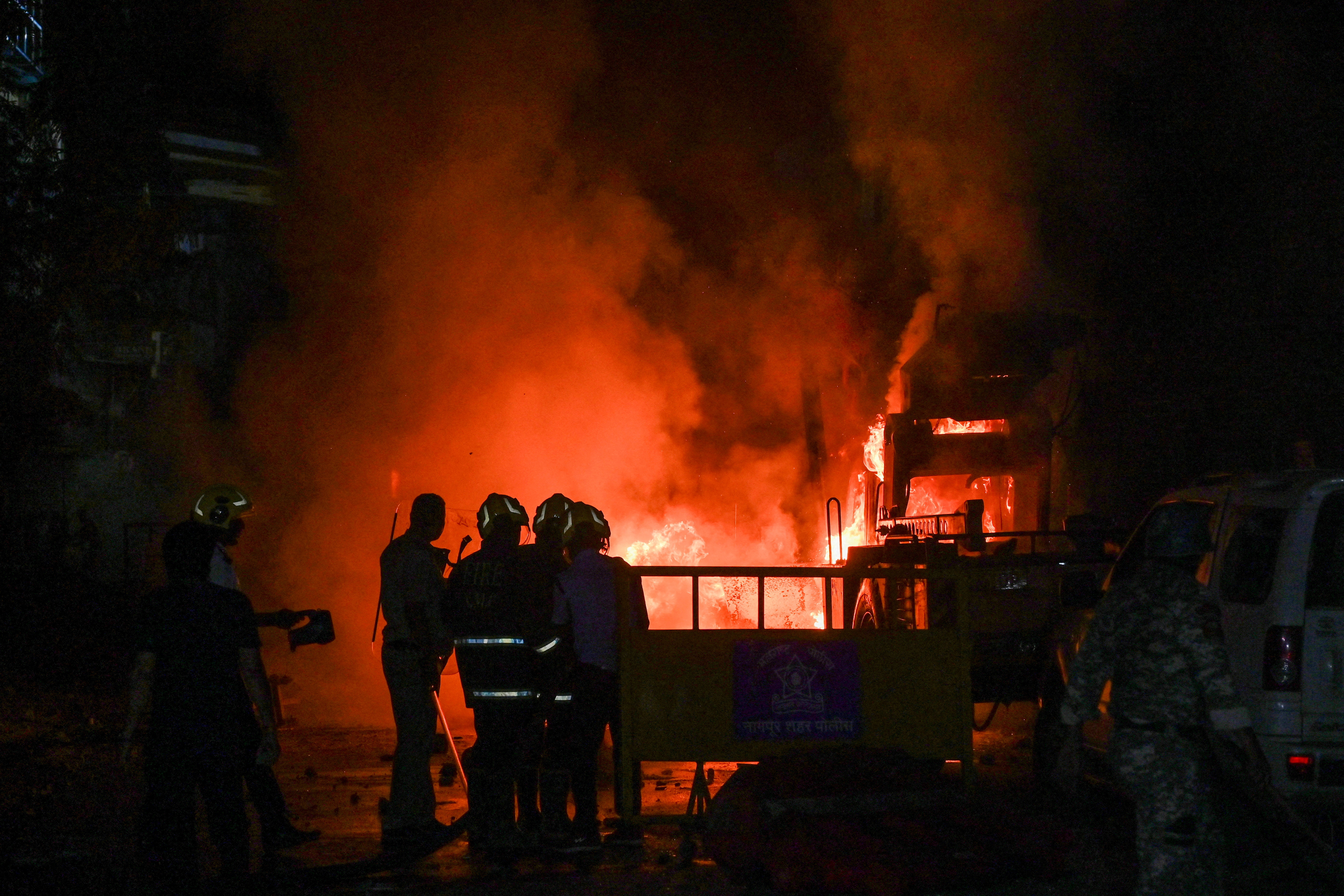 FILE PHOTO: Members of police stand as vehicles burn after clashes erupted due to demands over removal of the tomb of Mughal emperor Aurangzeb, in Nagpur
