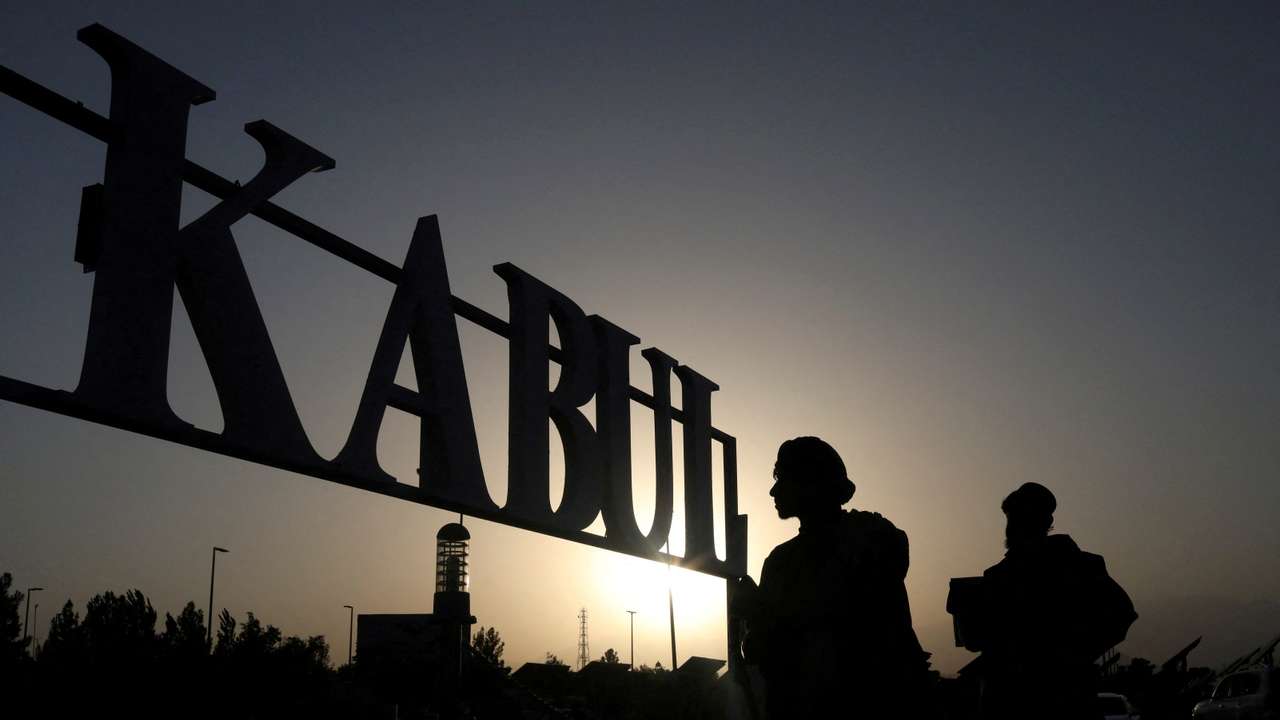 FILE PHOTO: Taliban soldiers stand in front of a sign at the international airport in Kabul